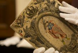 Embroidered binding thought to belong to Queen Henrietta Maria, wife of King Charles I, c1630 Colour photo of gloved hands holding colourfully embroidered historic binding thought to belong to Queen Henrietta Maria, wife of King Charles I, c1630
