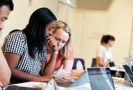 Two women and a man working on laptops at a table