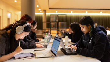 A group of university students studying at a high table within the Library.