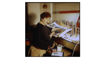 Fay Plamka, artist, in their artist studio in Caulfield. Paintbrush in mouth and hands on a canvas.