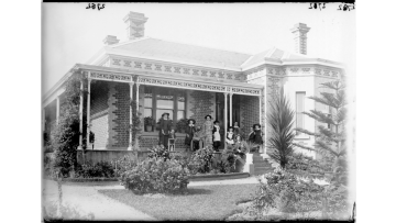 Black and white photograph of a family posed on verandah of house, probably in Melbourne