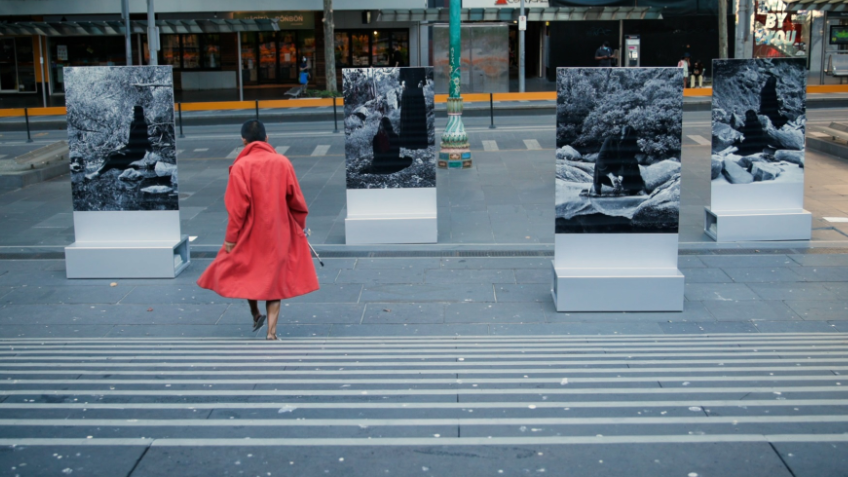Grey city scene with a person walking in a red coat