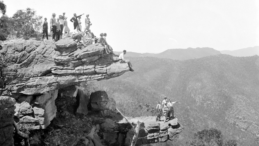 Black and white photo of people standing on a cliff face