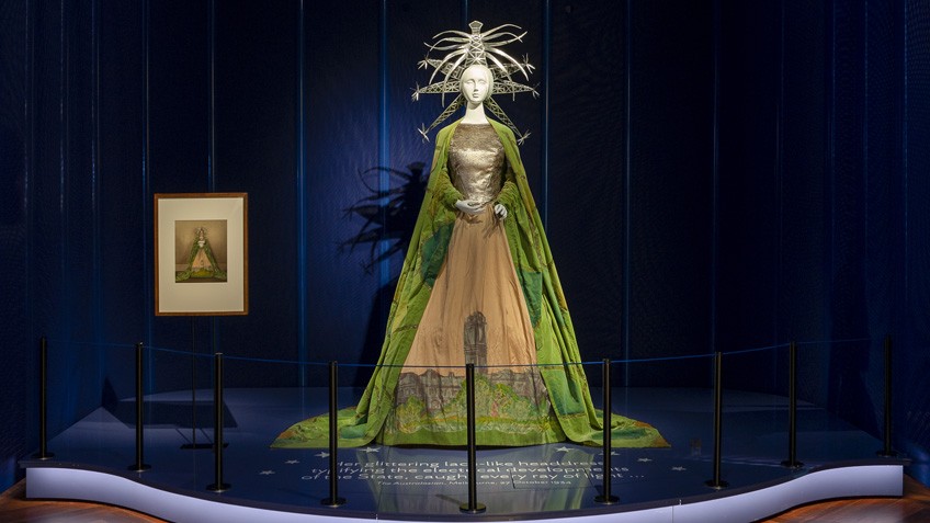 A mannequin on display wears a majestic cloak and a striking headdress