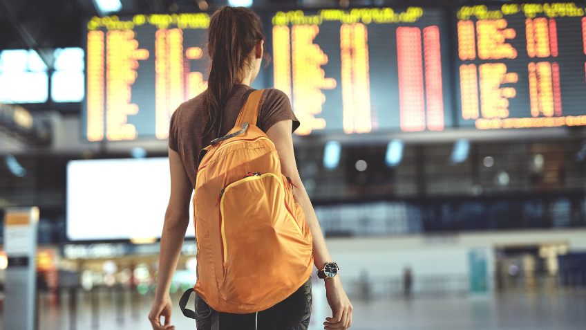Woman standing in front of an airport arrivals board