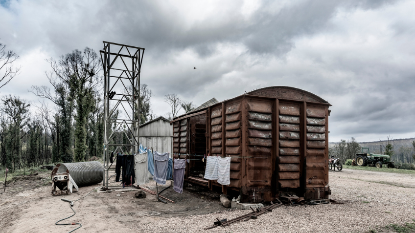A burnt out train carriage with grey skies behind it