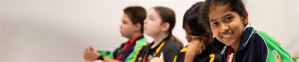 Group of students in a writing workshop. The student on the far right is looking directly at the camera and smiling.