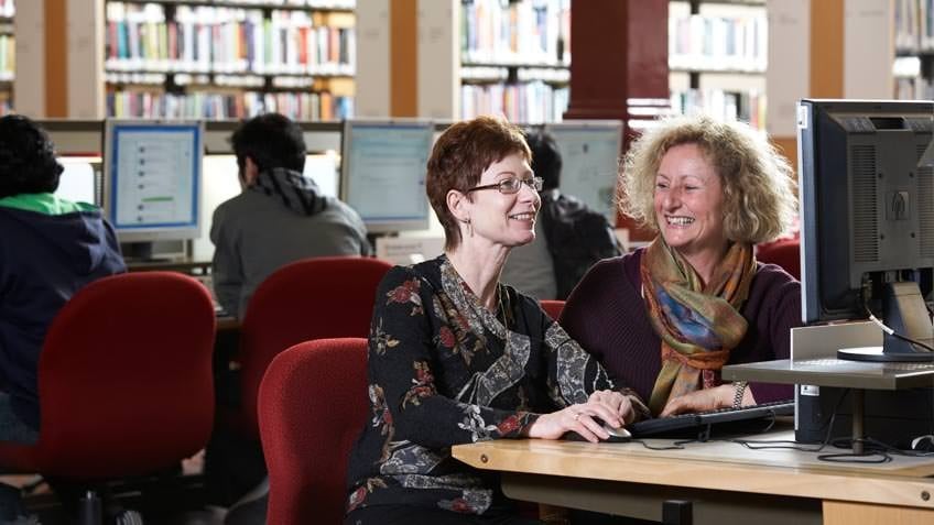 Colour photo of two women using a computer in the Redmond Barry Reading Room, State Library Victoria