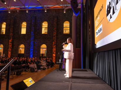 Woman presenting on stage to sold out crowd