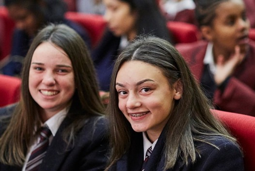 Two smiling, female high school students in uniform