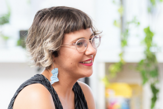 Woman smiling to her side with a black top and blue earrings 