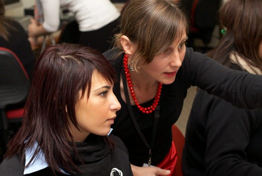 A teacher assists a female Year 12 student at a computer