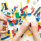 An image of two kids hands playing with colourful LEGO
